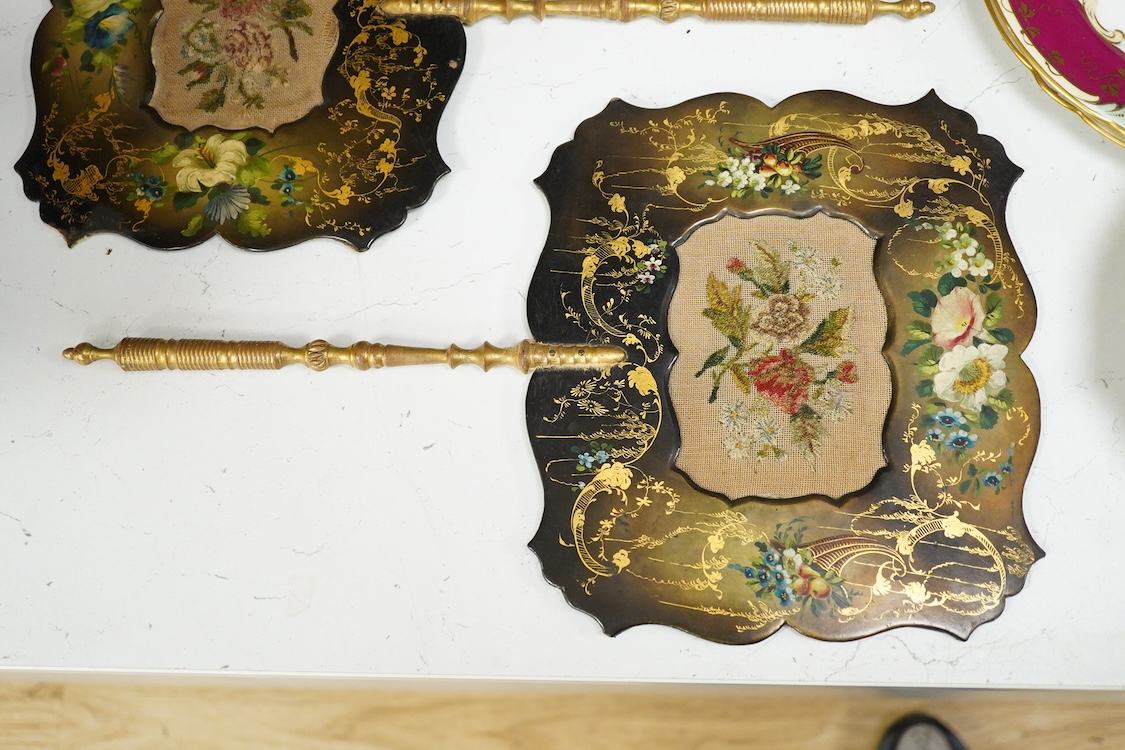 A pair of early Victorian papier maché hand screens, each with embroidered with cross stitched flowers, 41cm in length